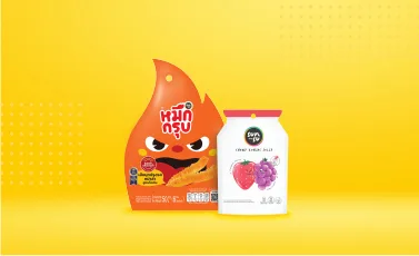 A หมึกกรุบ squid-snack pack and a SUNSU jelly pack against a yellow backdrop